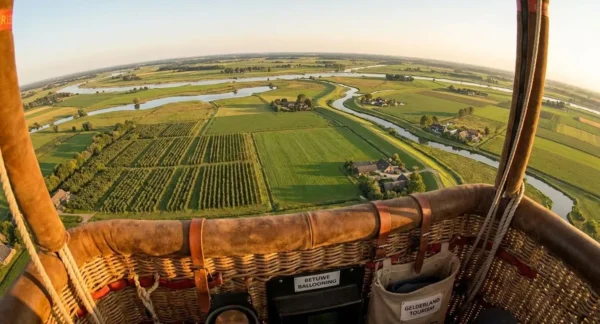 Uitzicht vanuit een luchtballon op de Betuwe met fruitboomgaarden, slingerend rivieren en ordelijke velden